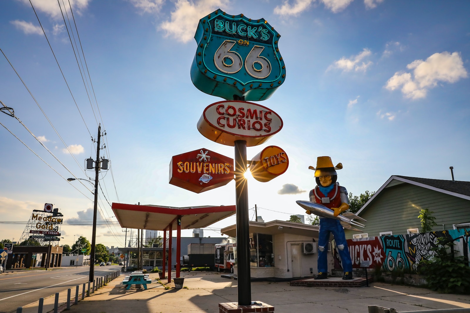 Route 66 a statue of a cowboy holding a surfboard in front of a gas station