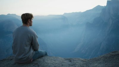 meditation man in gray shirt sits on cliff
